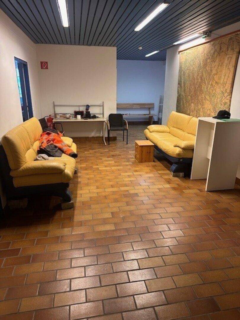 Aufenthaltsbereich mit gelben Sofas, Fliesenboden und einer großen Karte an der Wand.