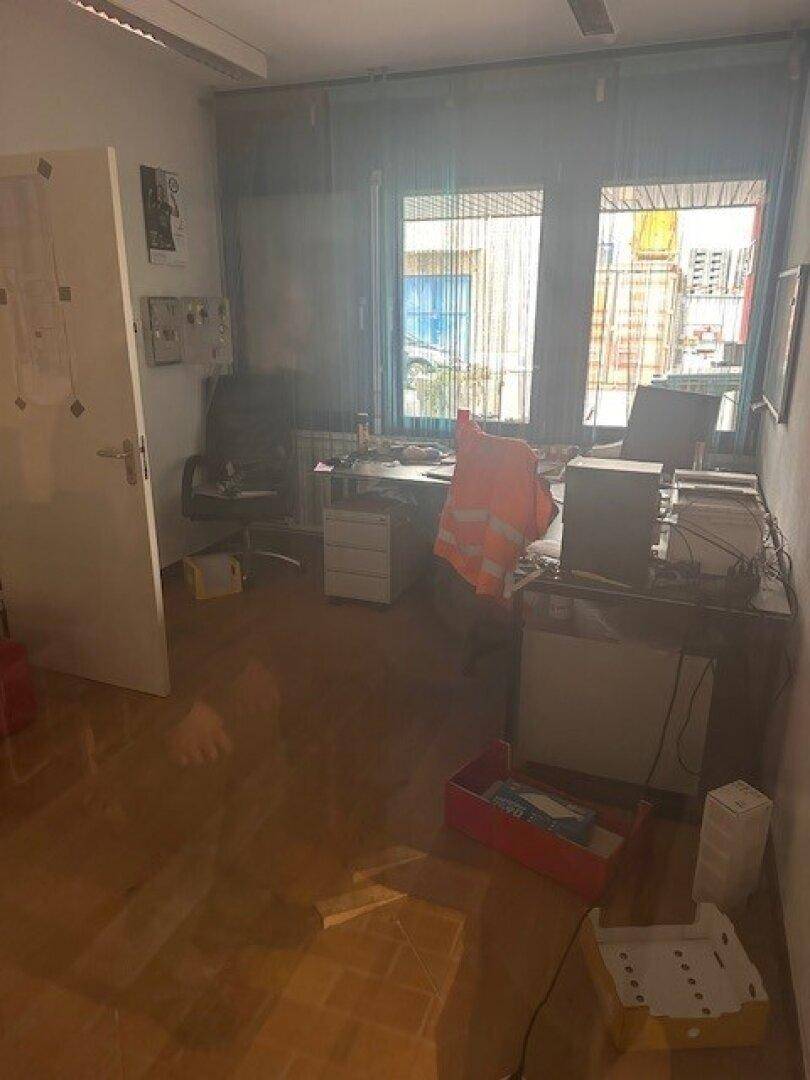 Kleines Büro mit Holzboden, Schreibtisch und Blick auf die Umgebung durch die Fenster.