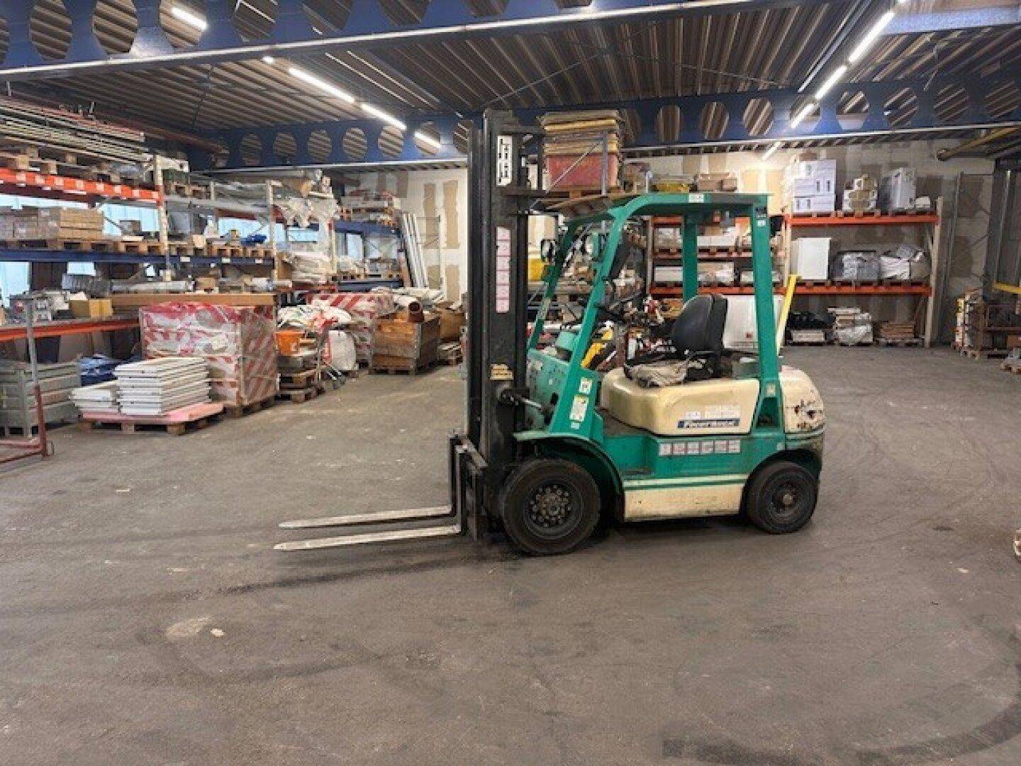 Gabelstapler in einer Lagerhalle, umgeben von Regalen und gelagerten Materialien.