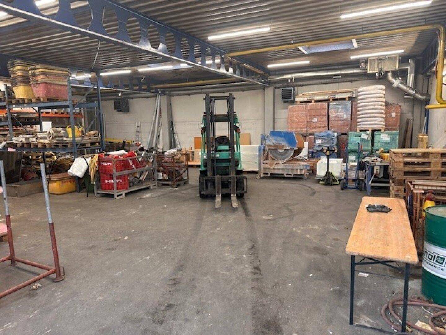 Weitläufige Lagerhalle mit Gabelstapler, Regalen voller Waren und industrieller Beleuchtung.