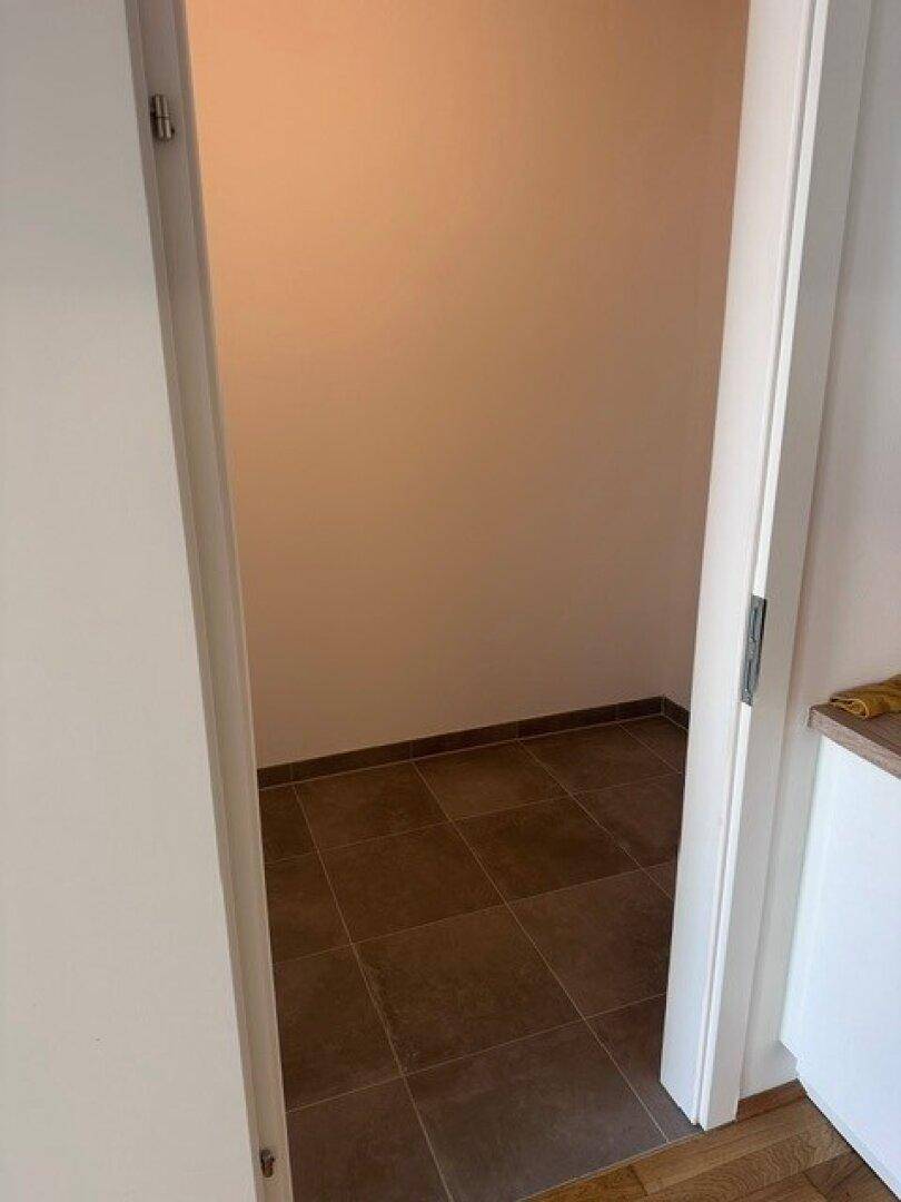 Kleiner Abstellraum mit dunklen Fliesen, ideal für zusätzlichen Stauraum im Haushalt.