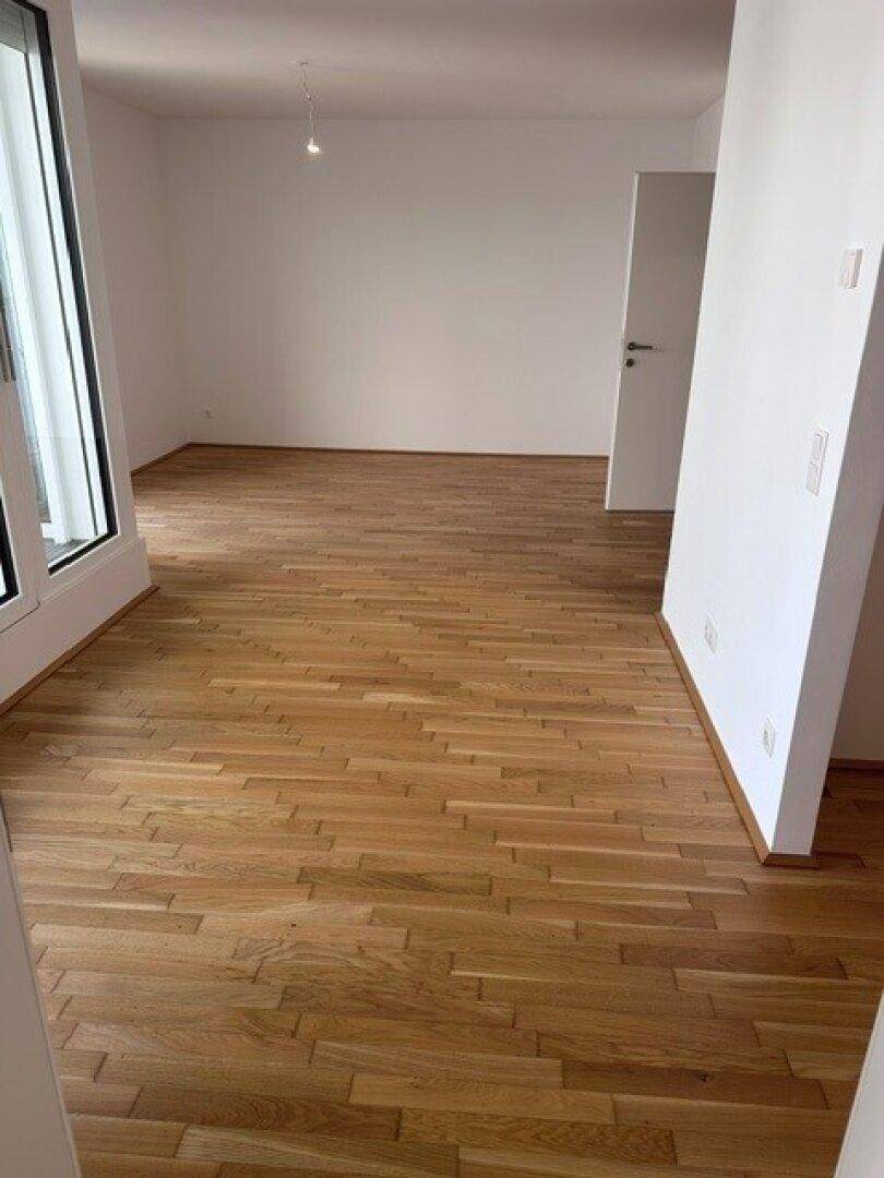 Geräumiger, leerer Raum mit hellem Parkettboden und großen Fenstern, bereit zur individuellen Gestaltung.