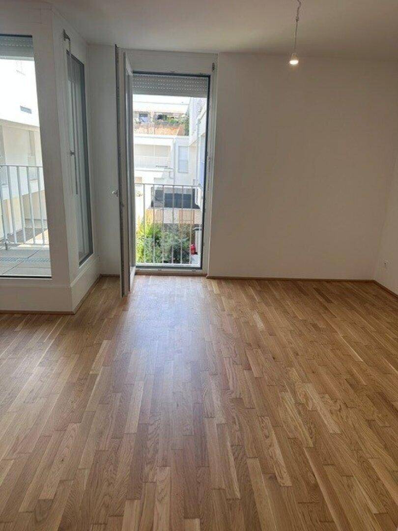 Helles Schlafzimmer mit Parkettboden und Zugang zu einem kleinen Balkon, ideal für frische Luft.