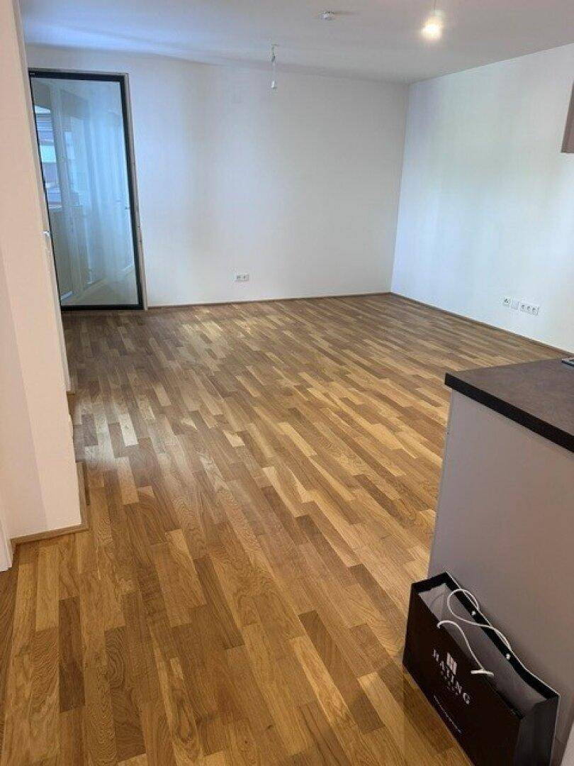 Geräumiger Wohnbereich mit hellem Holzparkett und weiß gestrichenen Wänden, bereit zur Einrichtung.