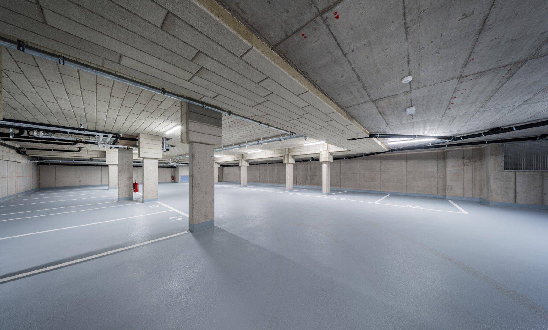 Geräumige Tiefgarage mit vielen Stellplätzen und Betonwänden in massiver Bauweise.
