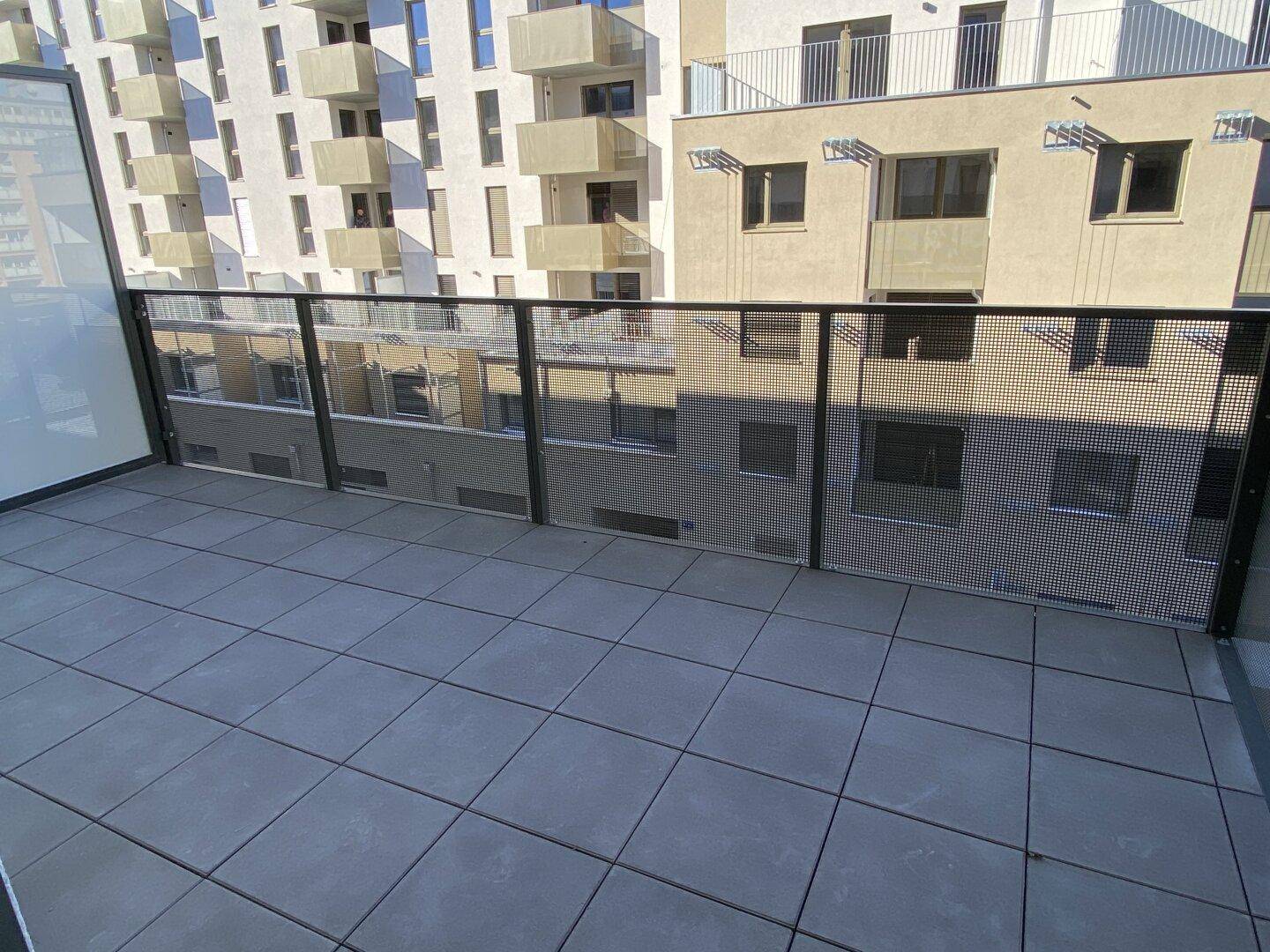 Geräumiger Balkon mit Fliesenboden und Blick auf die umliegenden Wohngebäude.