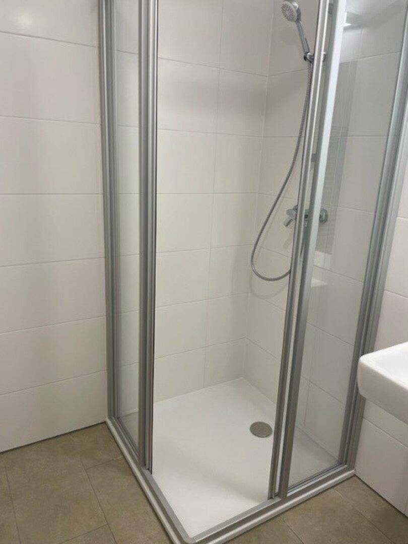Duschkabine mit Glaswänden und moderner Armatur im Badezimmer.
