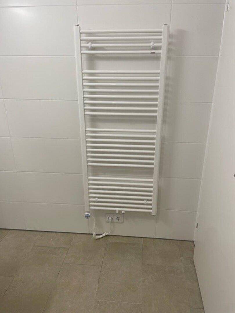 Badezimmer mit praktischem beheiztem Handtuchhalter an der gefliesten Wand.