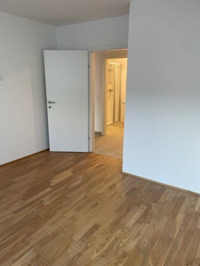 Schlafzimmer mit Parkettboden und Zugang zu einem angrenzenden Badezimmer.