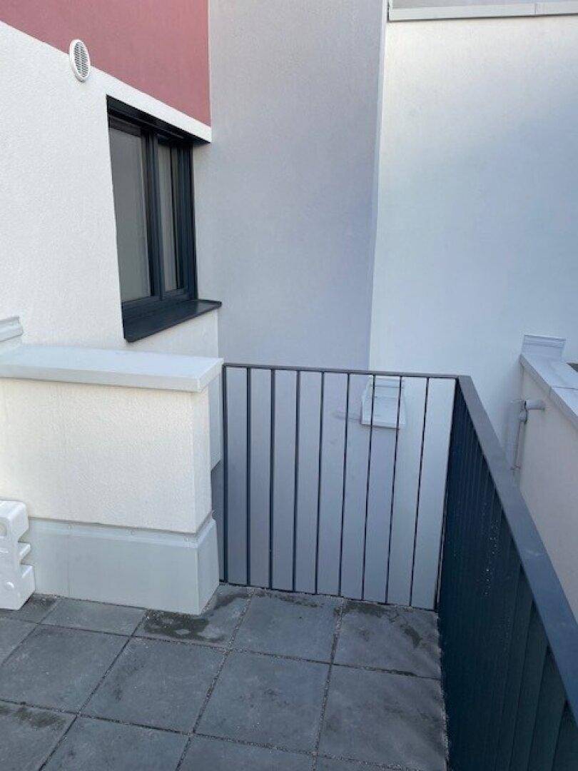 Teilansicht der Terrasse mit Fliesenboden und schlichtem Metallgeländer.
