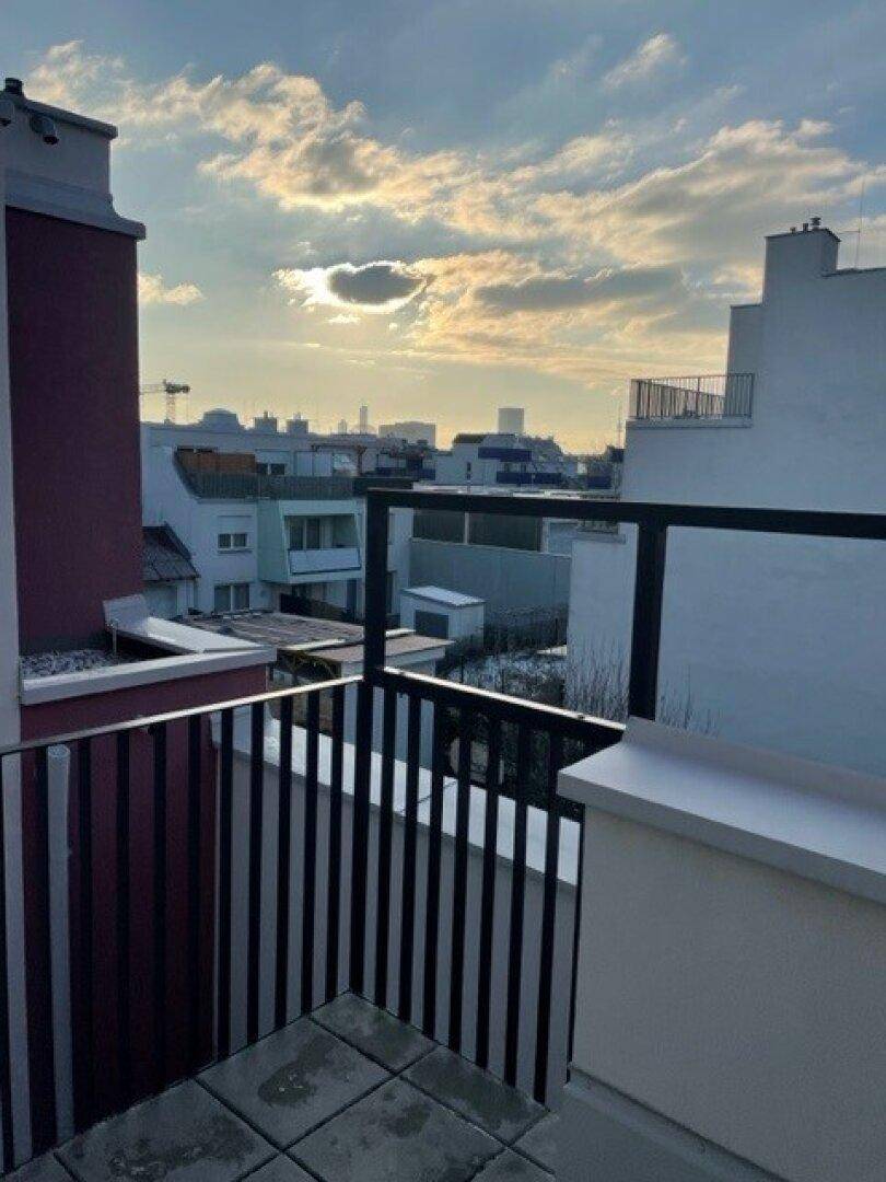 Weitläufiger Blick von der Terrasse über die Dächer der Stadt bei Sonnenuntergang.