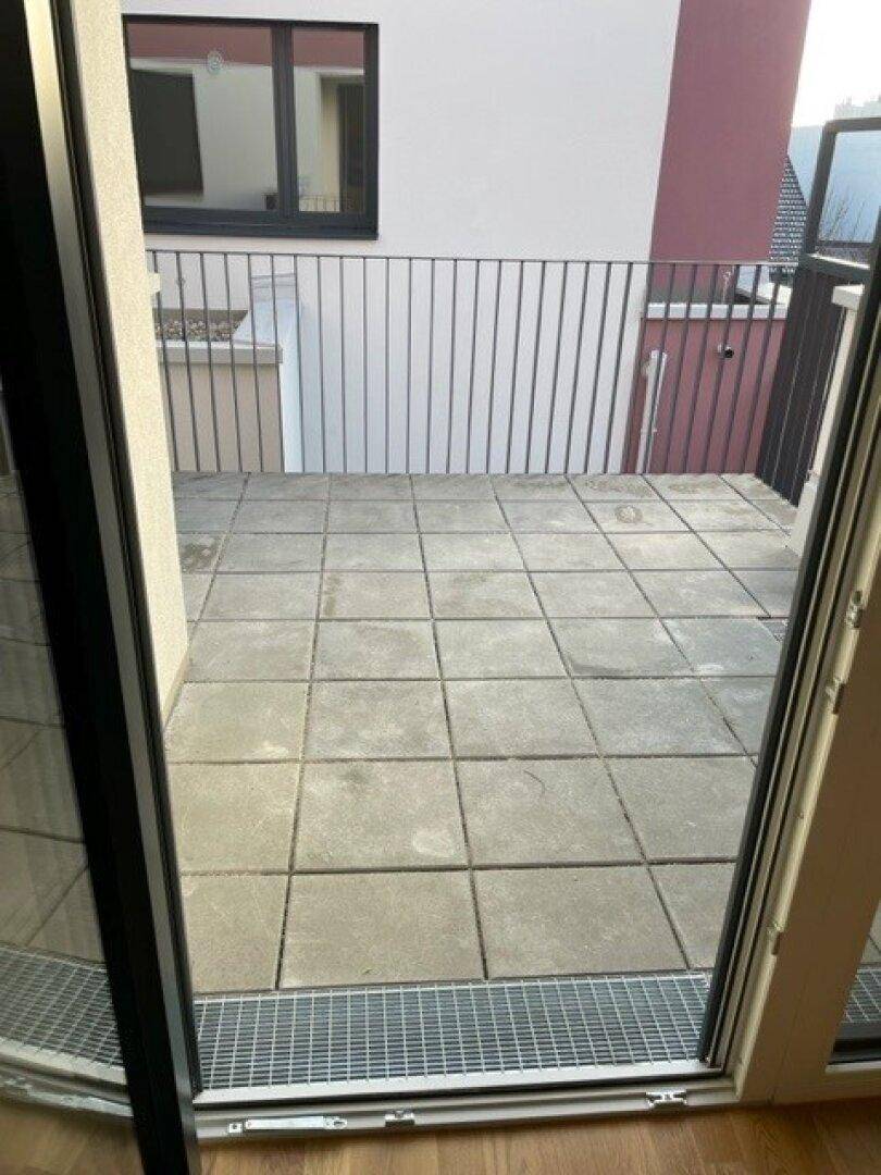 Geräumige Terrasse mit Fliesenboden und modernem Geländer, ideal für Entspannung.