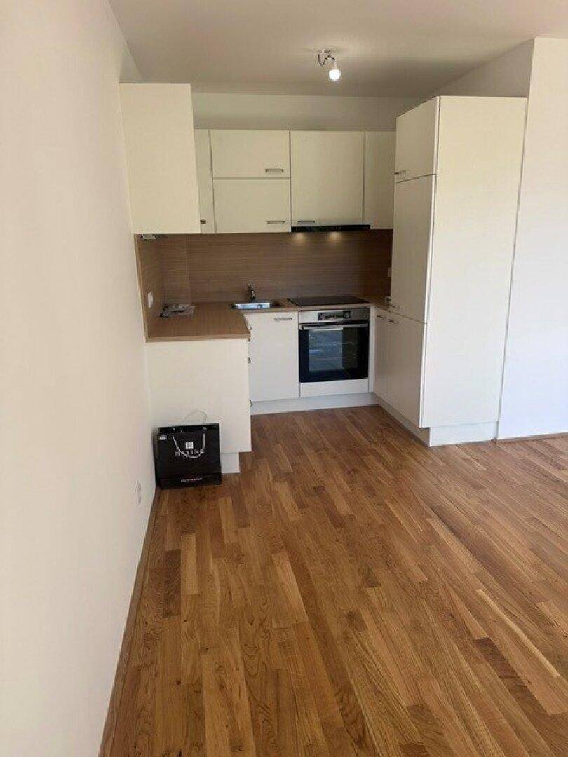 Moderne Küchenzeile mit weißen Schränken und integrierten Geräten, kombiniert mit Holzboden.
