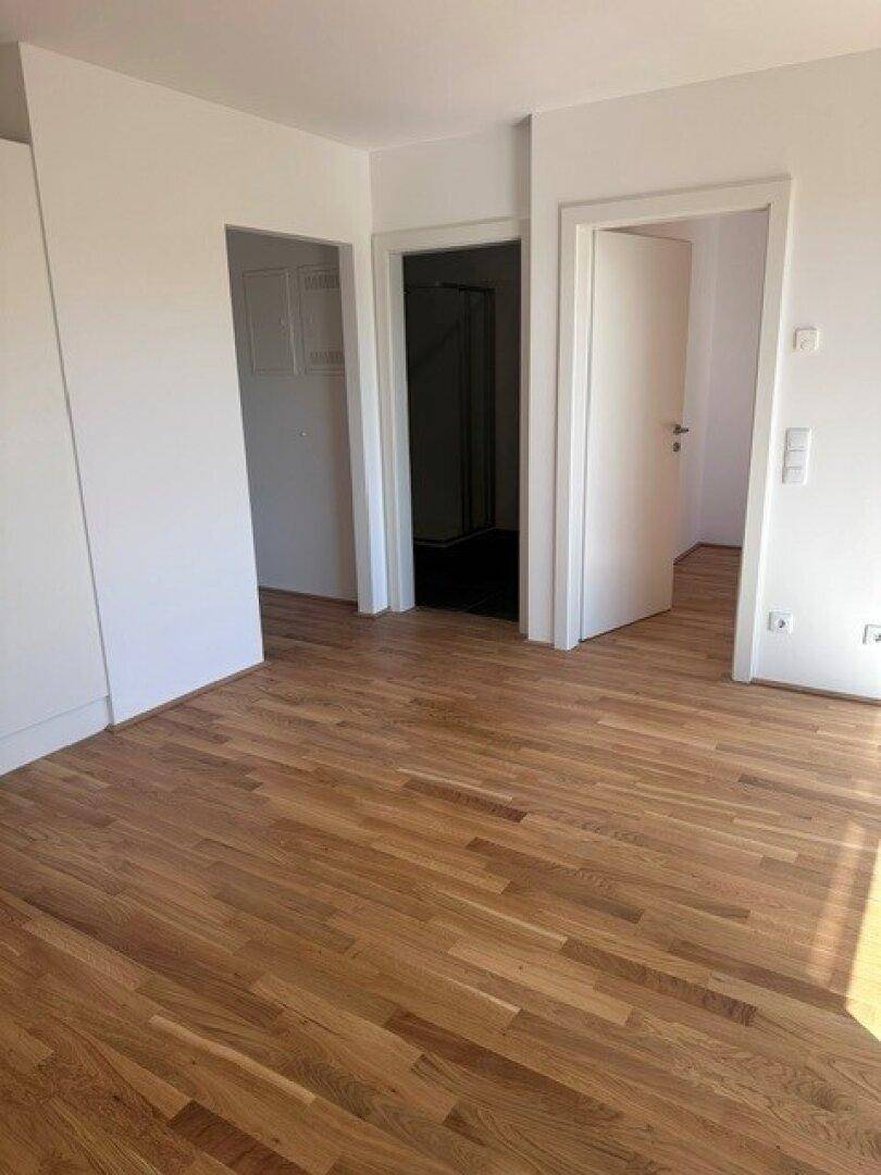 Heller Flur mit Holzboden und mehreren Türen, die zu verschiedenen Zimmern führen.