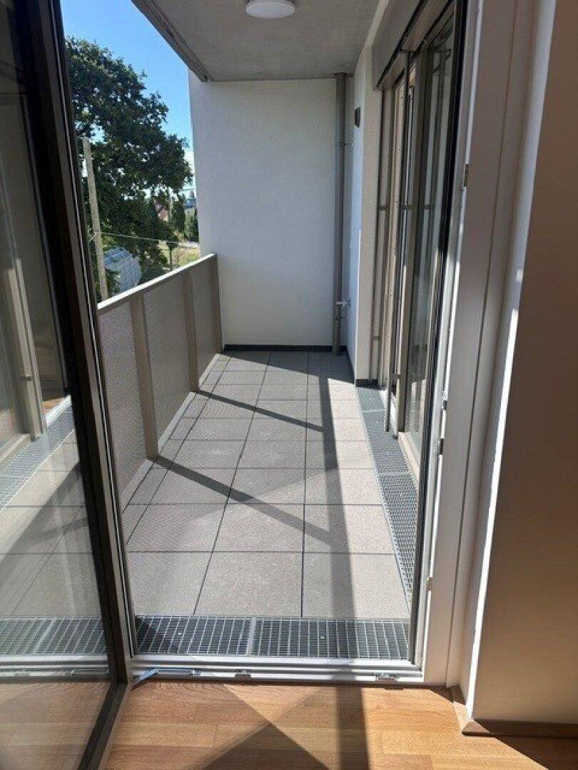 Langer, schmaler Balkon mit Fliesenboden und Metallgeländer, bietet Platz im Freien.
