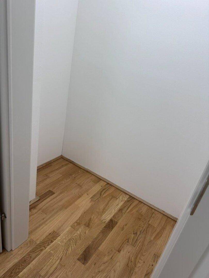 Kleiner Abstellraum mit hellem Parkettboden und weißen Wänden.