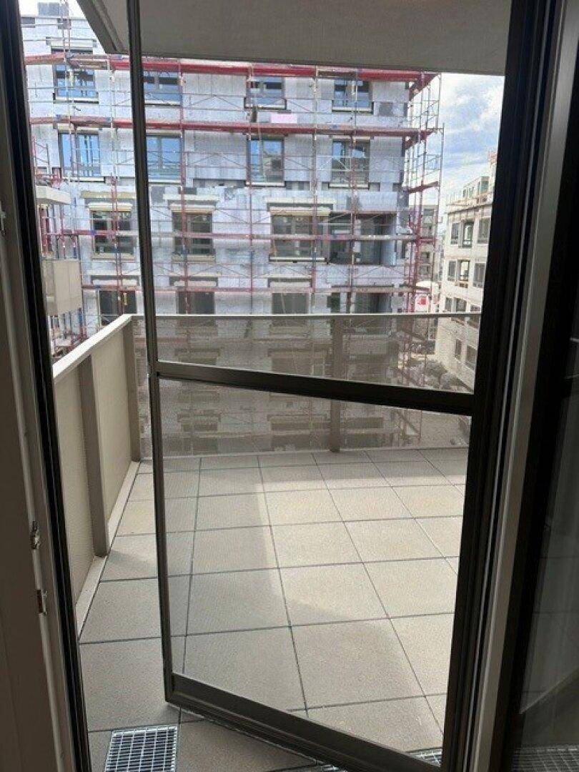 Geräumiger Balkon mit Fliesenboden und Blick auf die umliegende Baustelle.