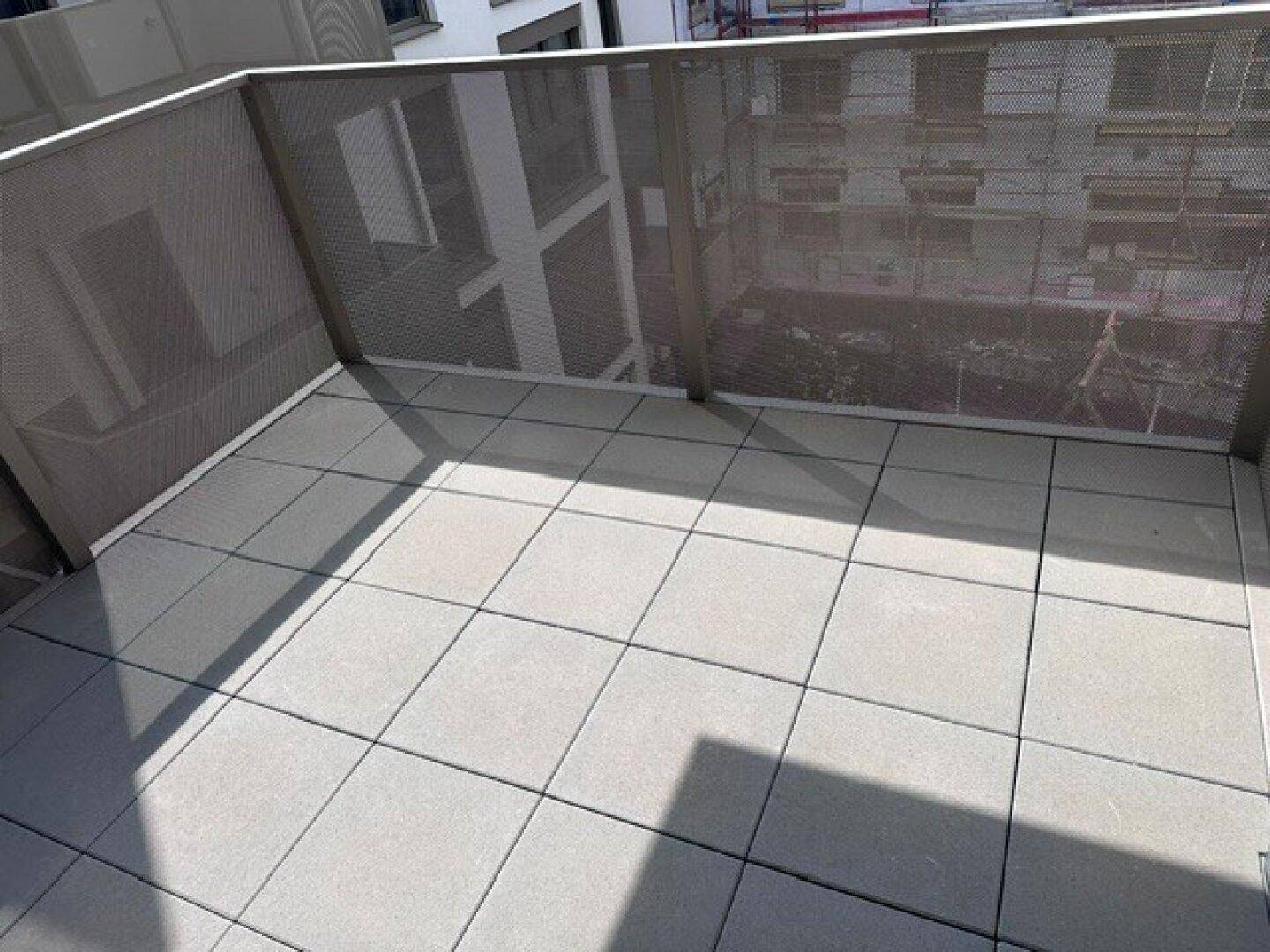Großer Balkon mit Fliesenboden und Metallgeländer, bietet Platz für Entspannung im Freien.