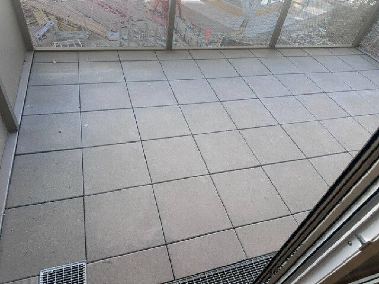 Gefliester Balkonboden mit Blick auf eine Baustelle im Hintergrund.