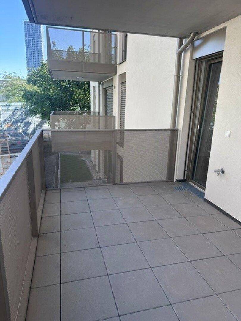 Geräumiger Balkon mit Fliesenboden und Metallgeländer, umgeben von ähnlichen Balkonen.