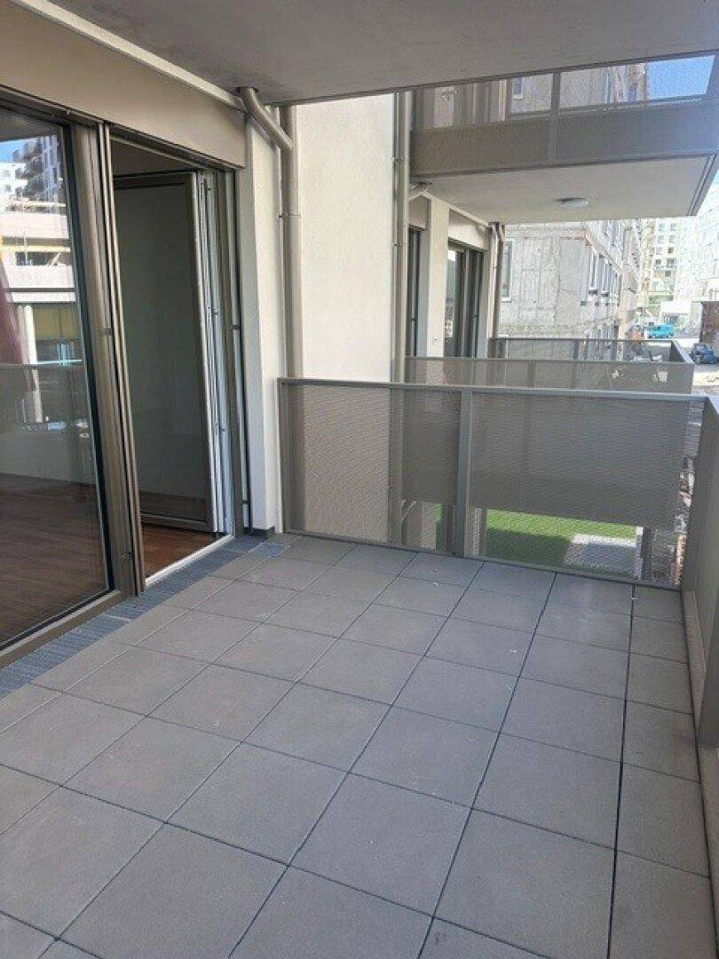 Heller Balkon mit Fliesenboden und Zugang zum Innenbereich der Wohnung.
