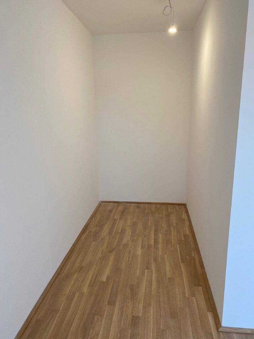 Kleiner, leerer Raum mit Holzboden und weißen Wänden, ideal als Abstellraum oder begehbarer Kleiderschrank.