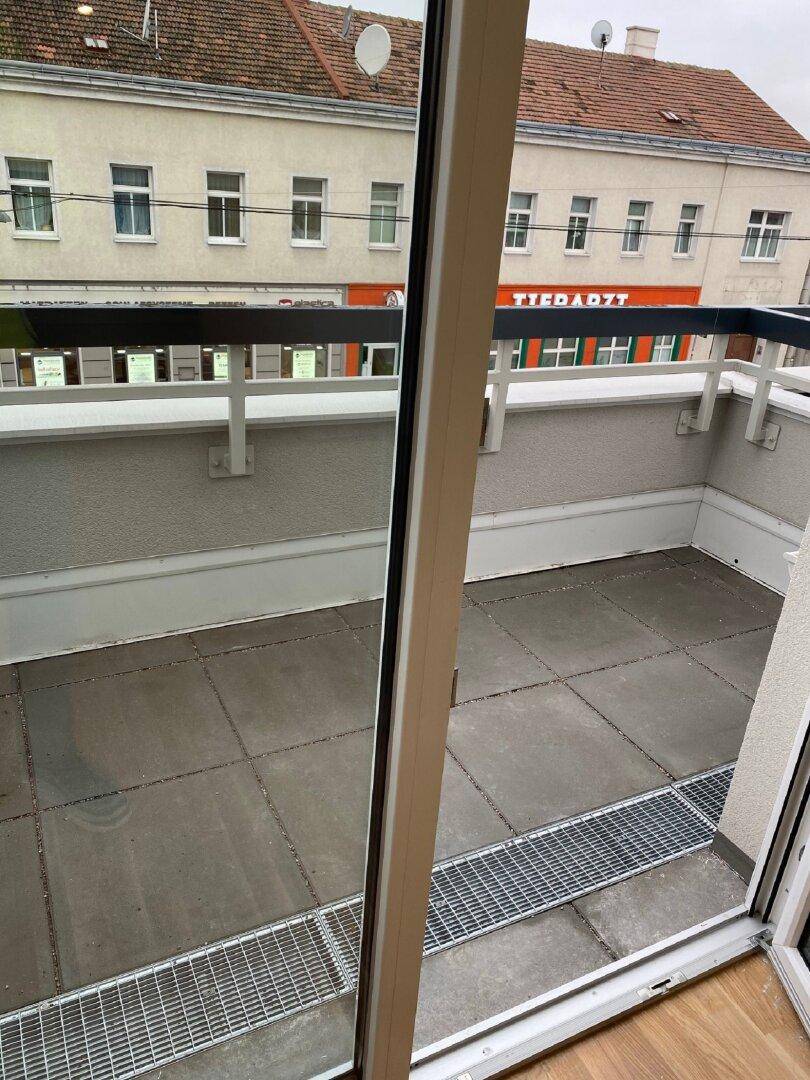 Detailansicht eines gefliesten Balkons mit Metallgeländer und Blick auf die gegenüberliegenden Gebäude.