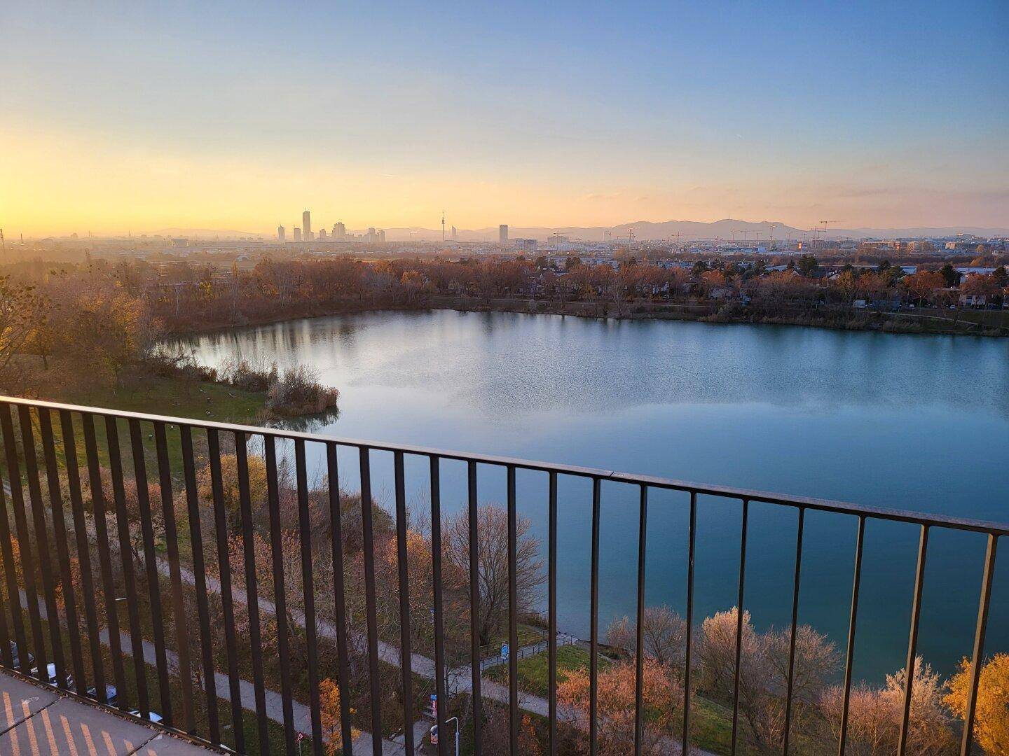 Atemberaubender Ausblick vom Balkon auf den glitzernden See und die Stadtsilhouette an einem sonnigen Tag.