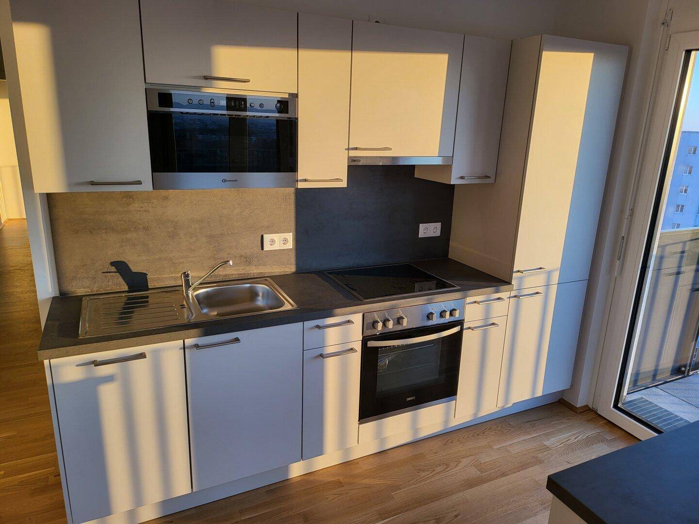Detailansicht der modernen Einbauküche mit Spüle, Induktionskochfeld und Backofen.