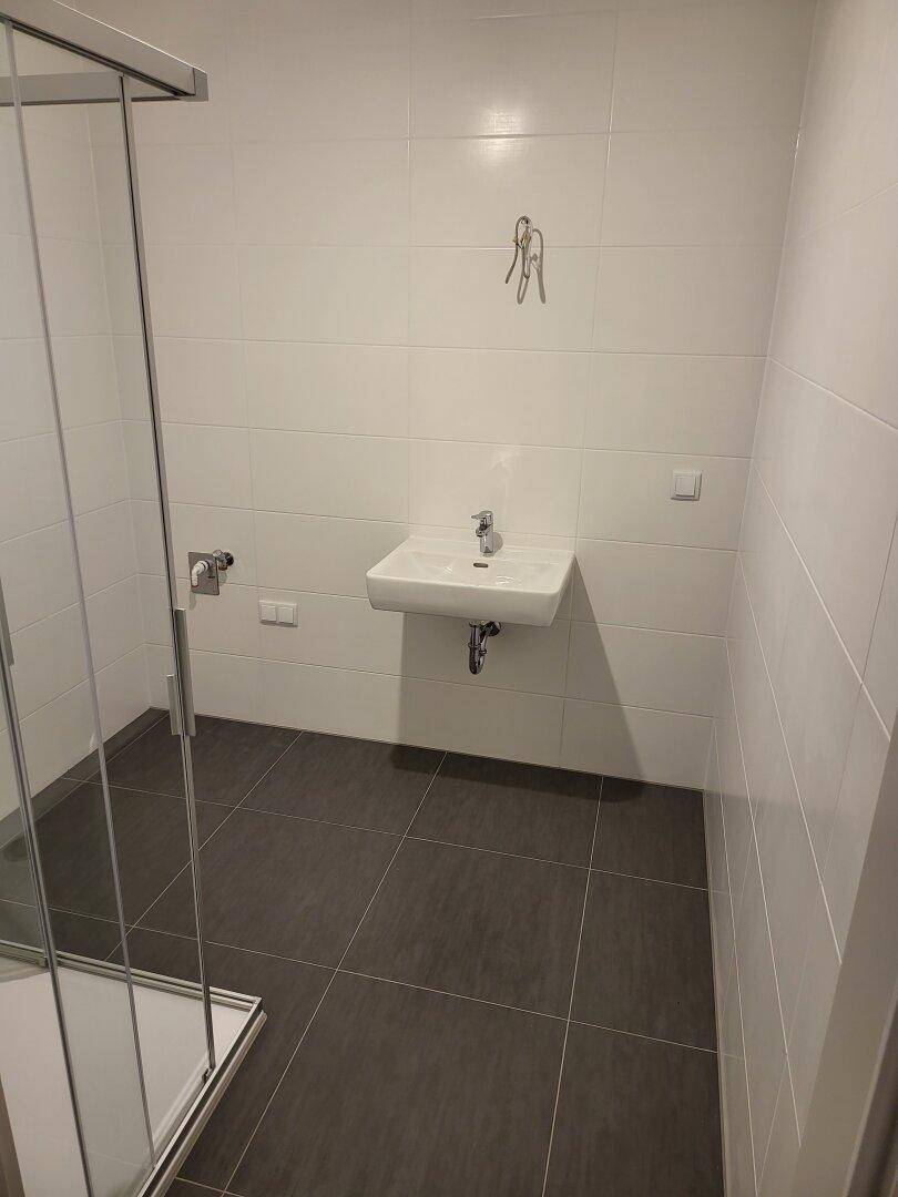 Helles Badezimmer mit wandhängendem Waschbecken und modernen Fliesen.