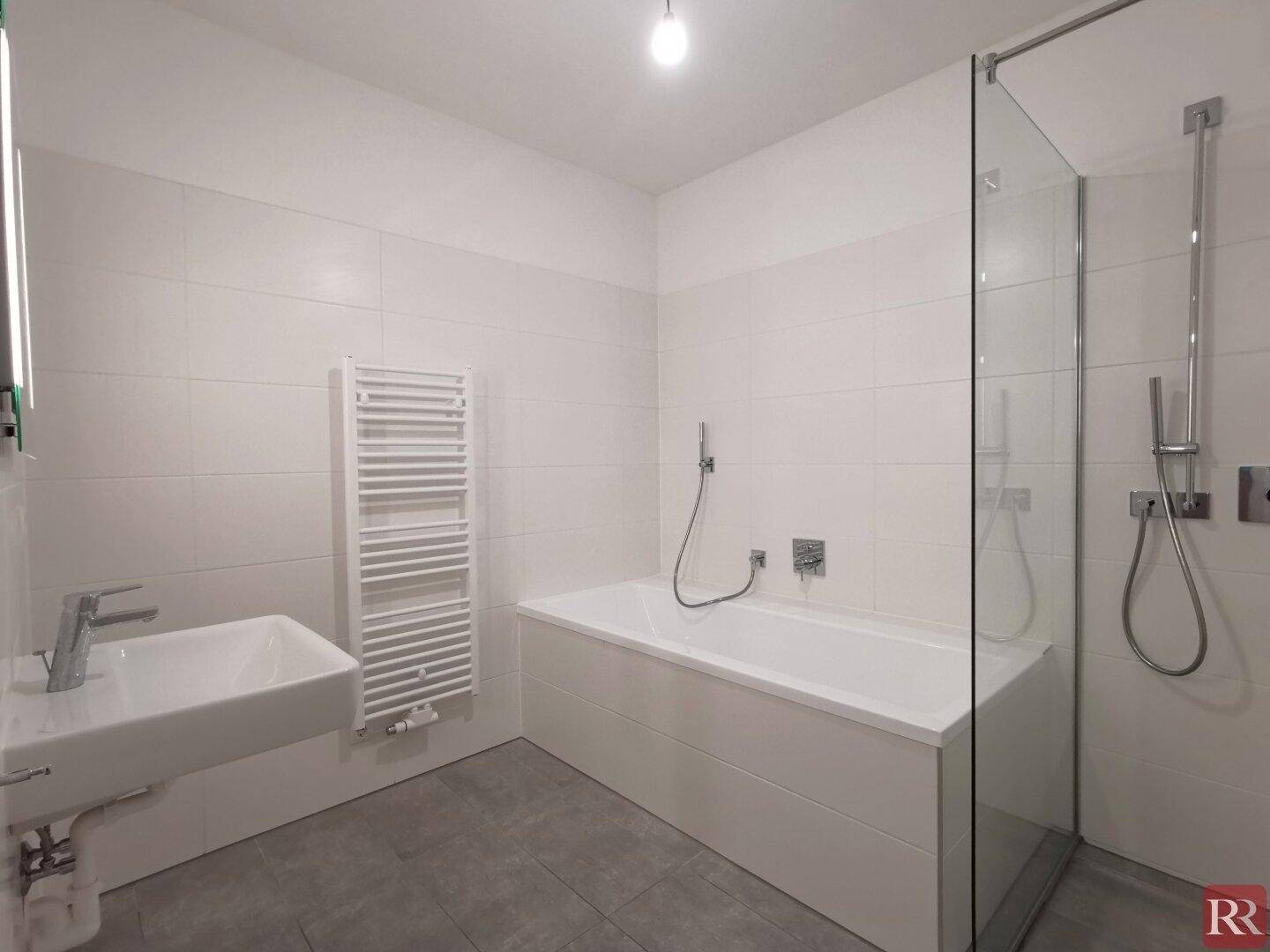 Modernes Badezimmer mit Badewanne, Duschbereich, Waschbecken und beheiztem Handtuchhalter.