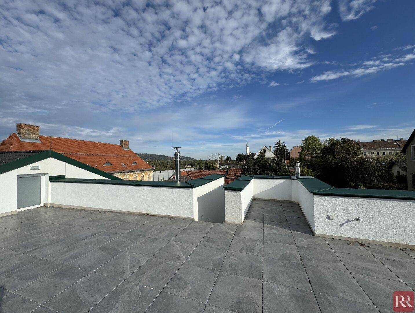 Geräumige Dachterrasse mit Fliesenboden und weitem Blick über die Umgebung.