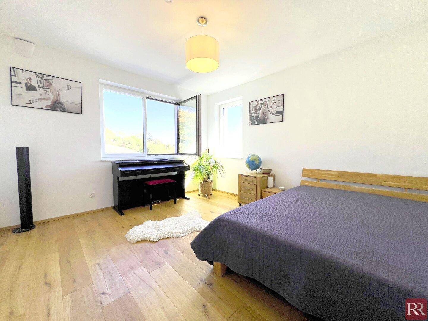 Schlafzimmer mit Holzboden, großem Fenster und Blick auf die umliegende Landschaft.