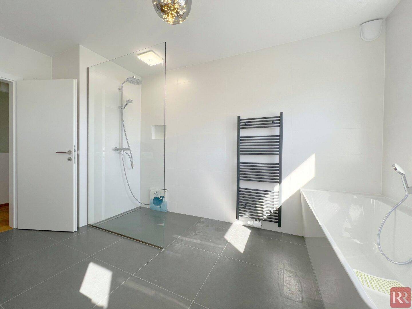 Geräumiges Badezimmer mit begehbarer Dusche, Badewanne und beheiztem Handtuchhalter.