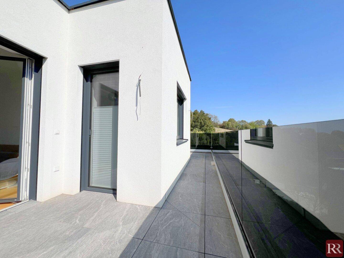 Moderne Dachterrasse mit Fliesenboden und Glasgeländer, ideal zum Entspannen.