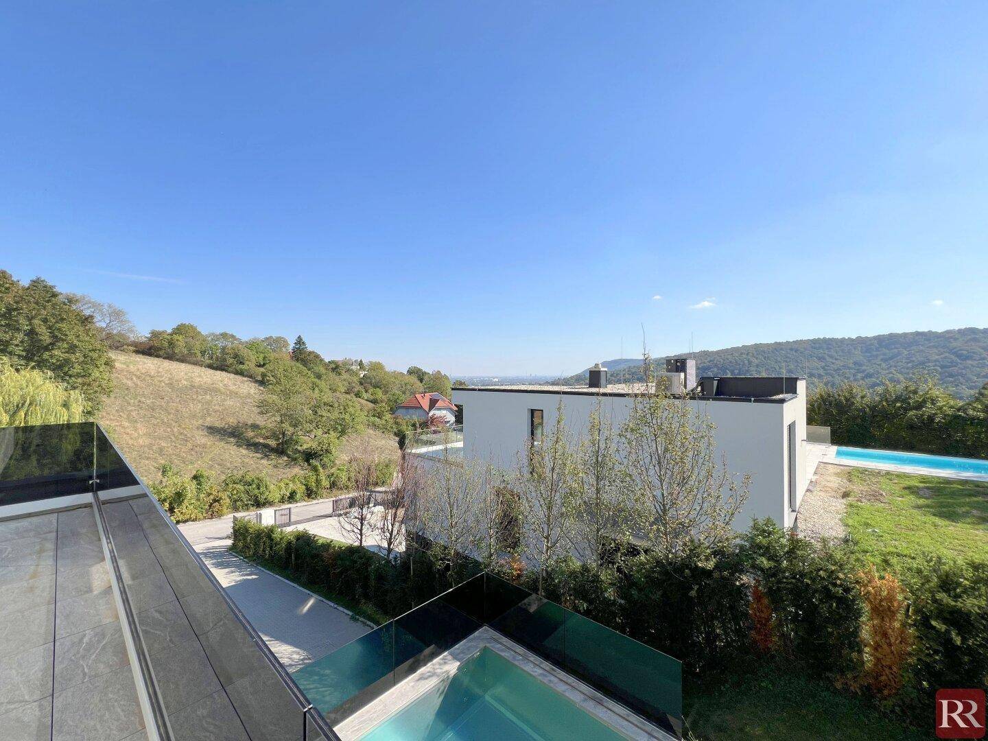 Weitläufiger Blick von der Terrasse auf die grüne Hügellandschaft und den Poolbereich.
