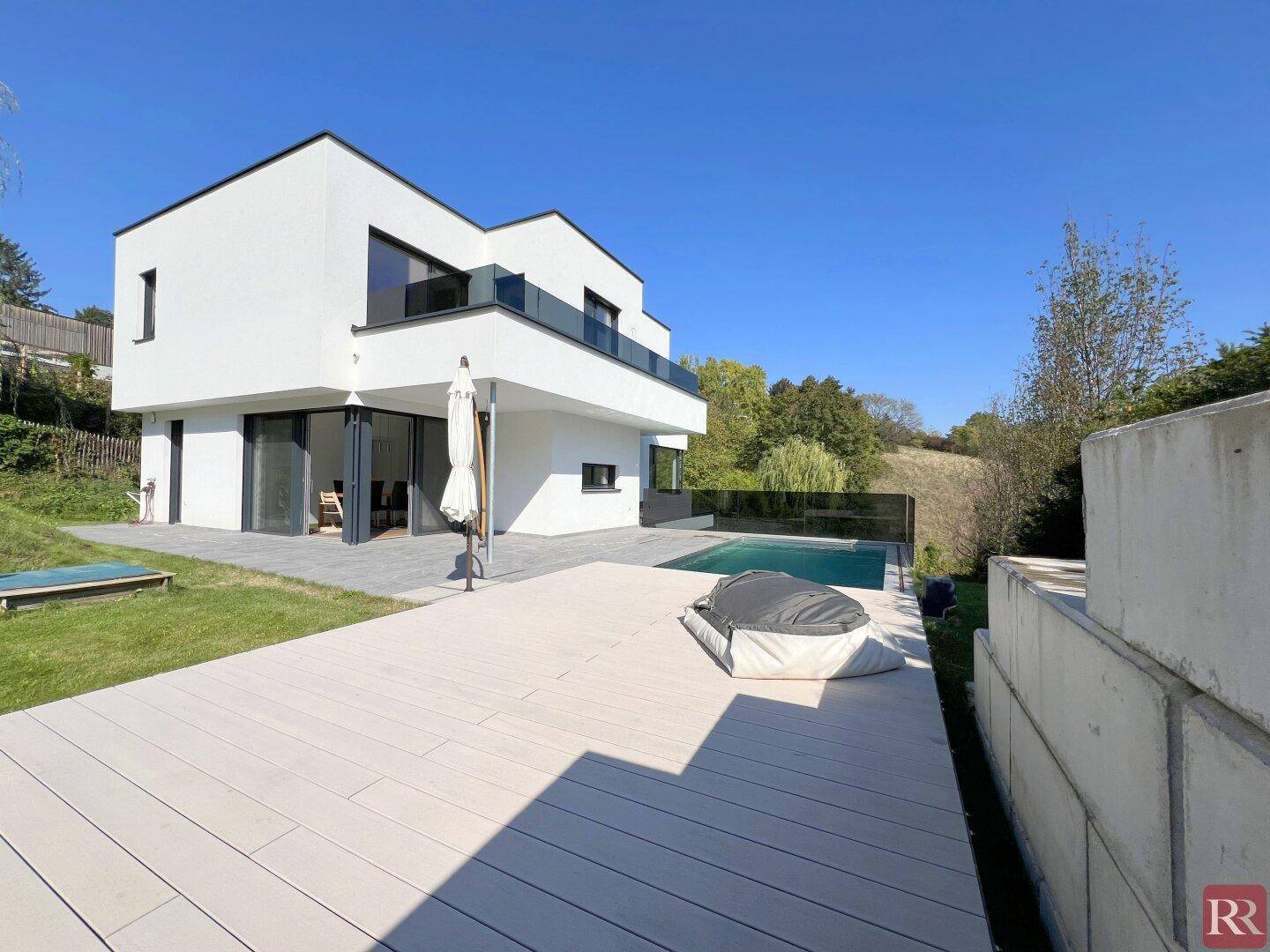 Modernes Haus mit großzügiger Terrasse, Pool und weitläufigem Gartenbereich.