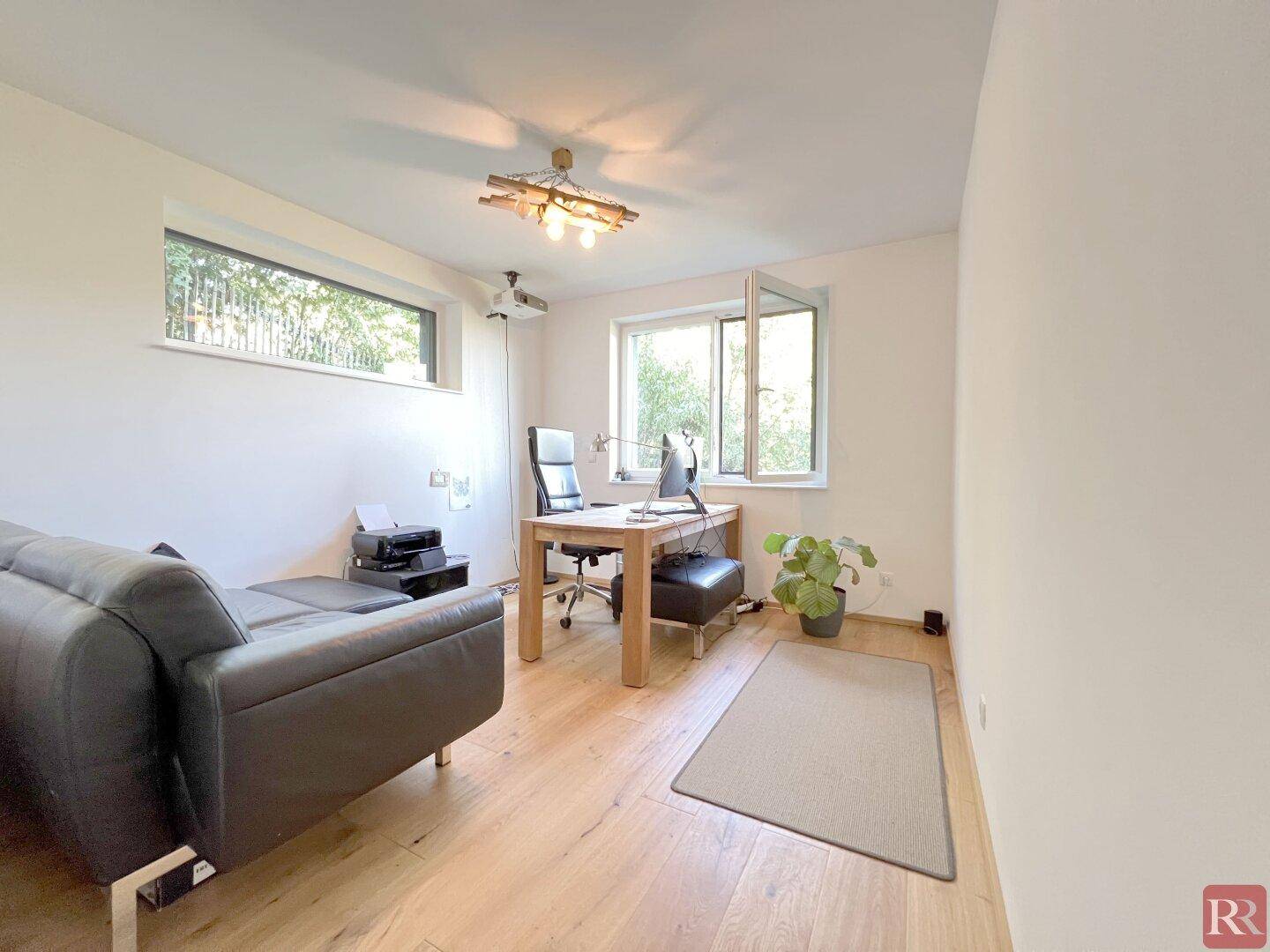 Helles Arbeitszimmer mit Holzboden, Schreibtisch und Blick ins Grüne.