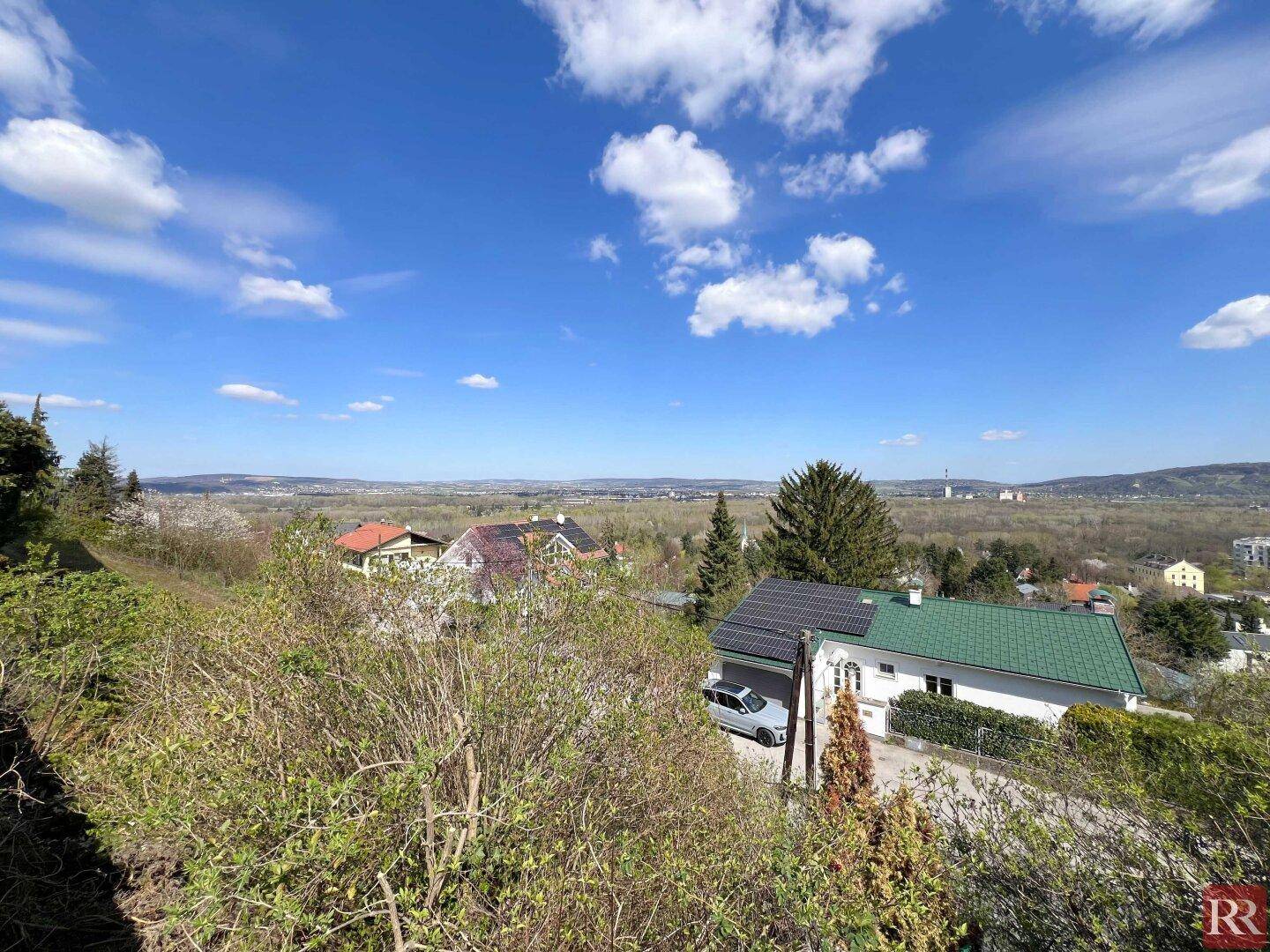 Weitläufiger Ausblick über eine Wohnsiedlung und die umliegende grüne Landschaft.