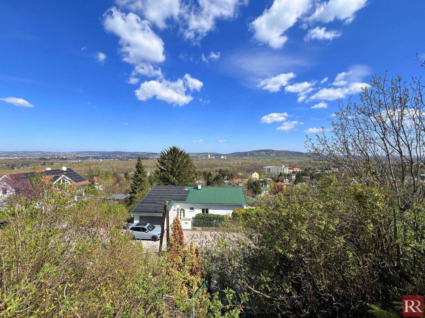 Panoramablick auf eine Wohngegend mit Häusern und weitem Horizont unter blauem Himmel.
