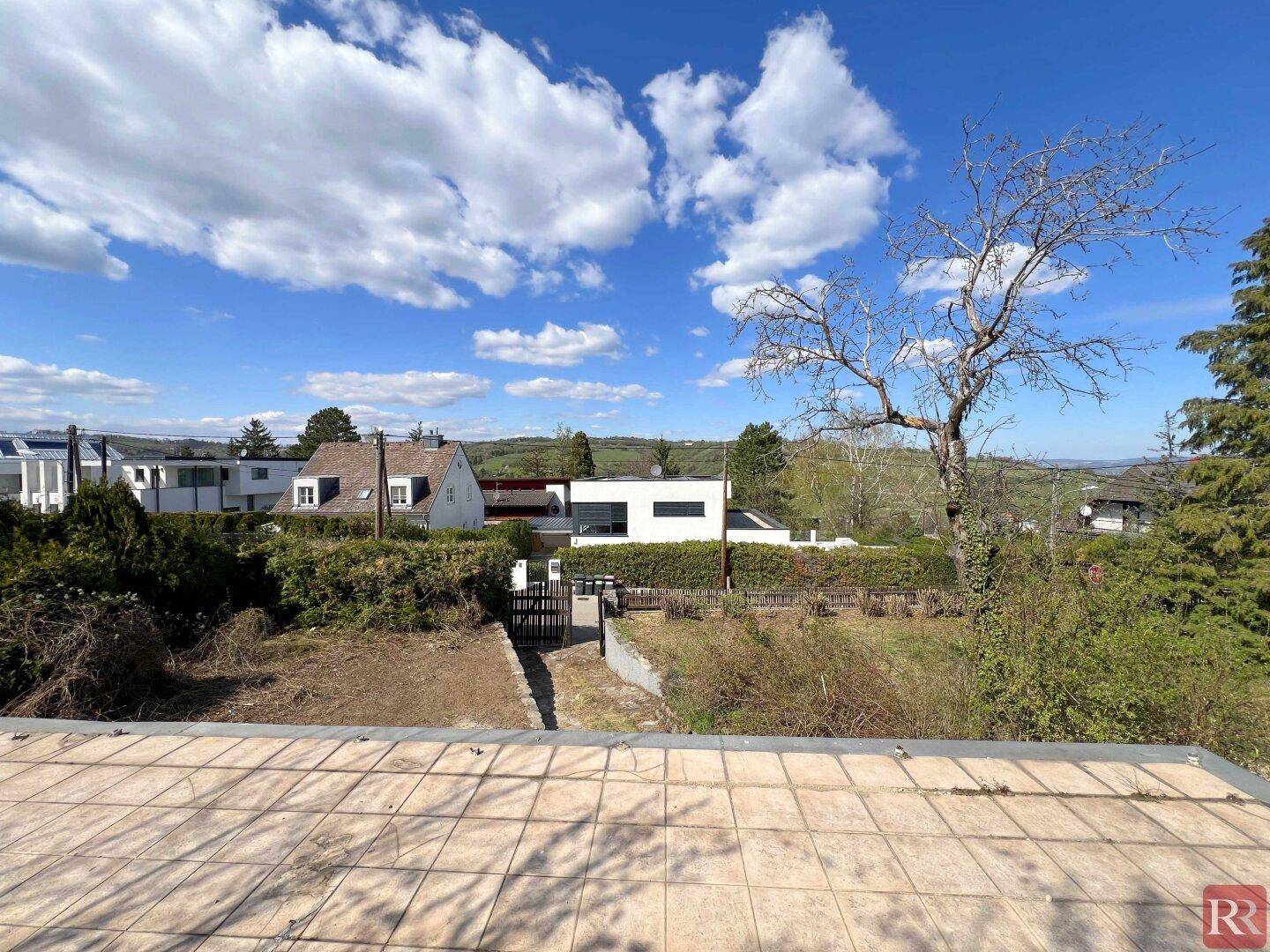 Weitblick über die umliegende Landschaft mit modernen und traditionellen Häusern unter einem bewölkten Himmel.