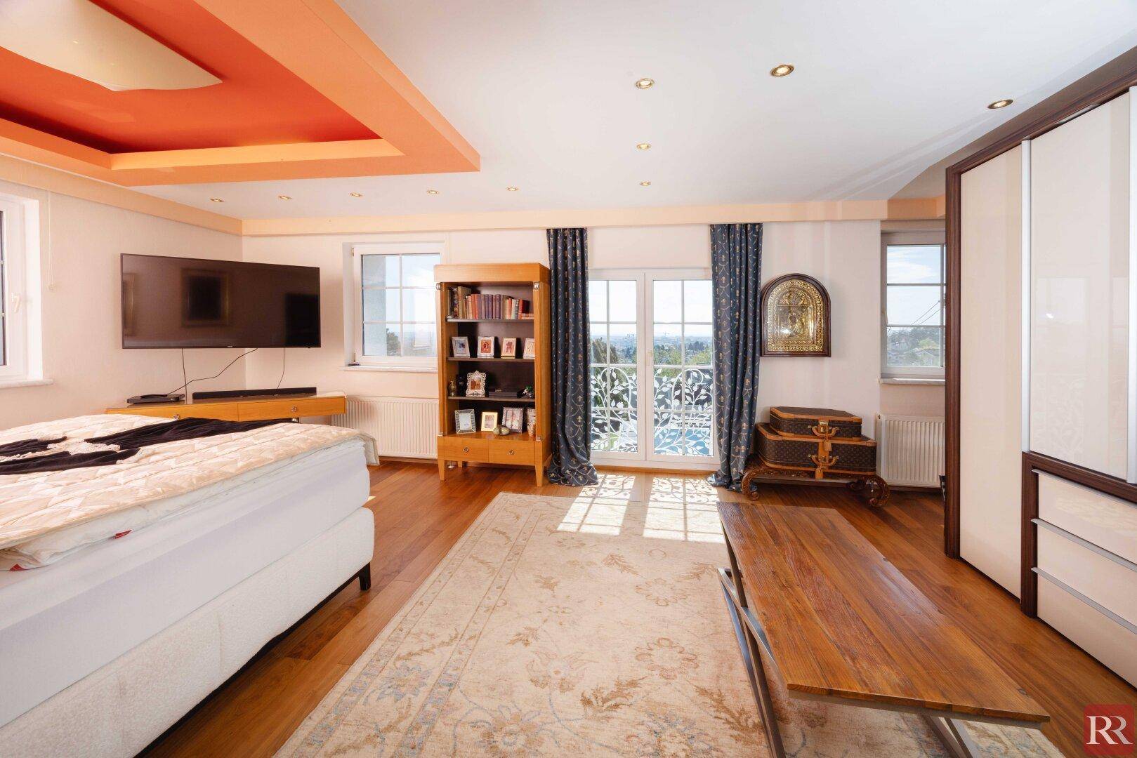 Helles Schlafzimmer mit Holzboden, Deckenbeleuchtung und Zugang zu einem französischen Balkon.