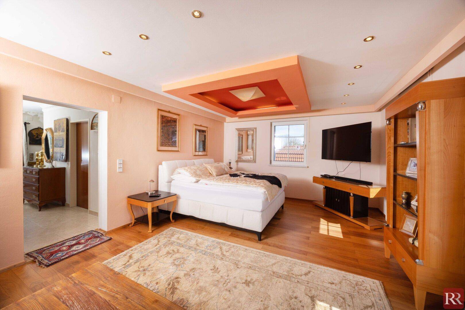 Geräumiges Schlafzimmer mit Holzboden, Deckenbeleuchtung und einem großen Bett, hell und einladend.