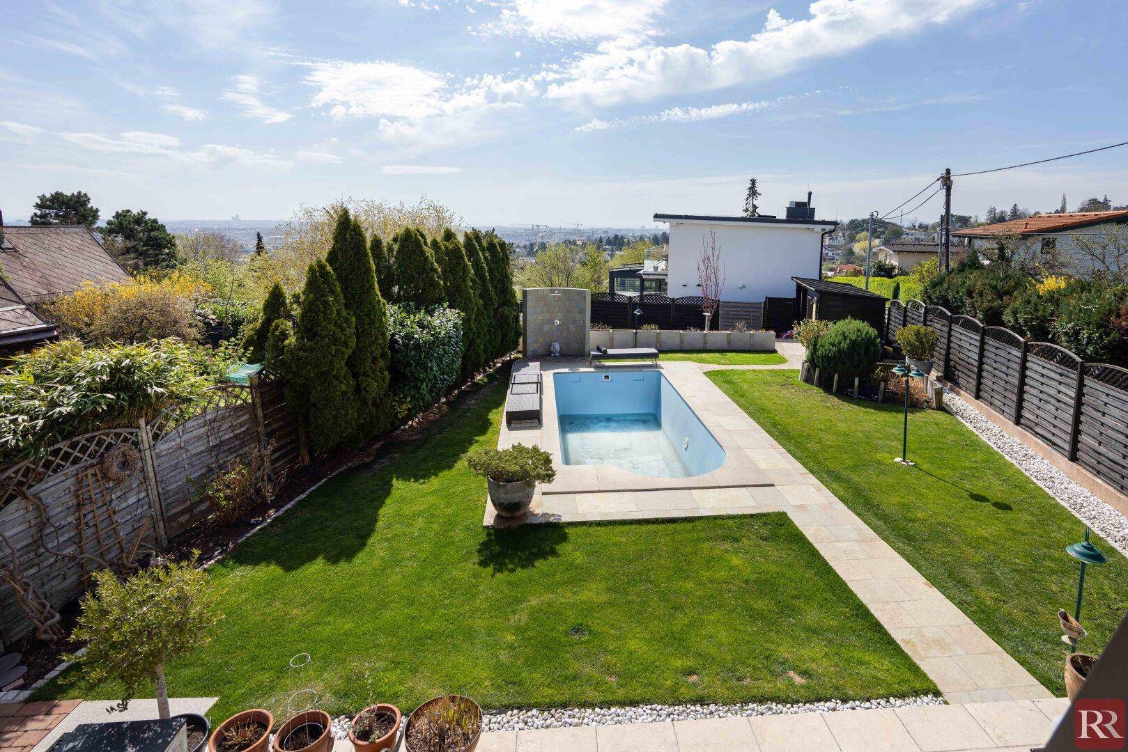Weitläufiger Garten mit Pool, gepflegtem Rasen und hohen Hecken, bietet Privatsphäre.