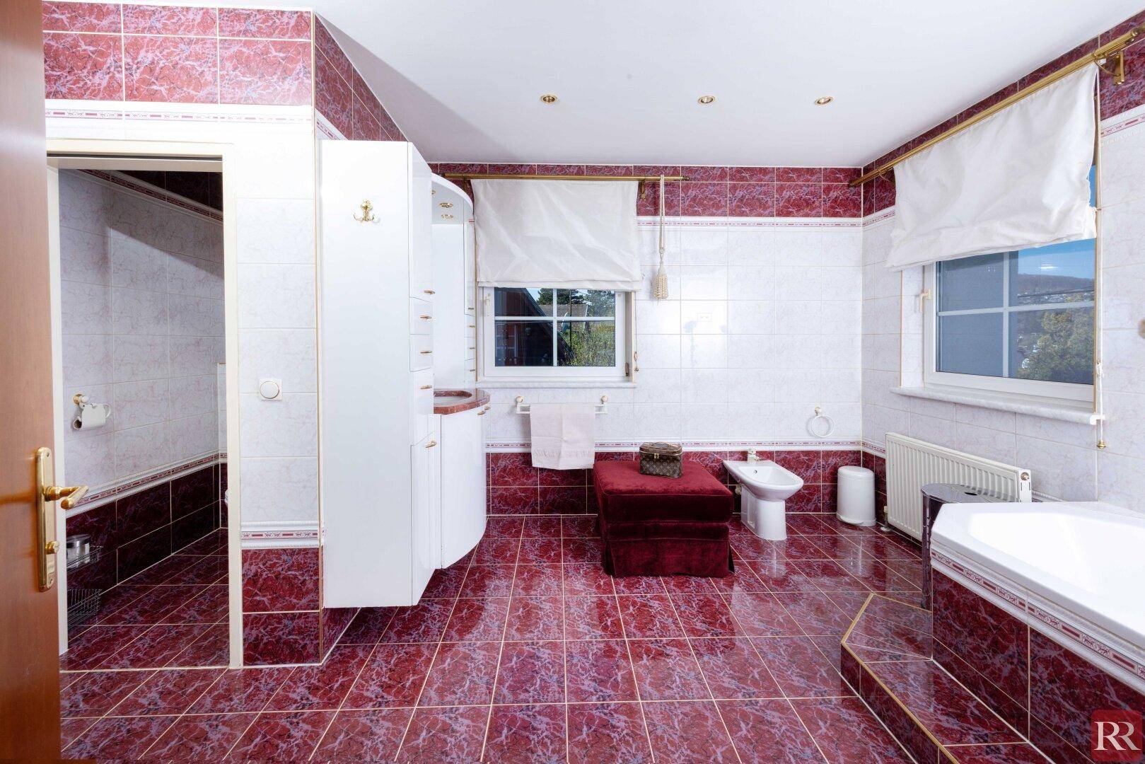 Geräumiges Badezimmer mit roten Fliesen, Dusche, Bidet und Fenster für natürliches Licht.