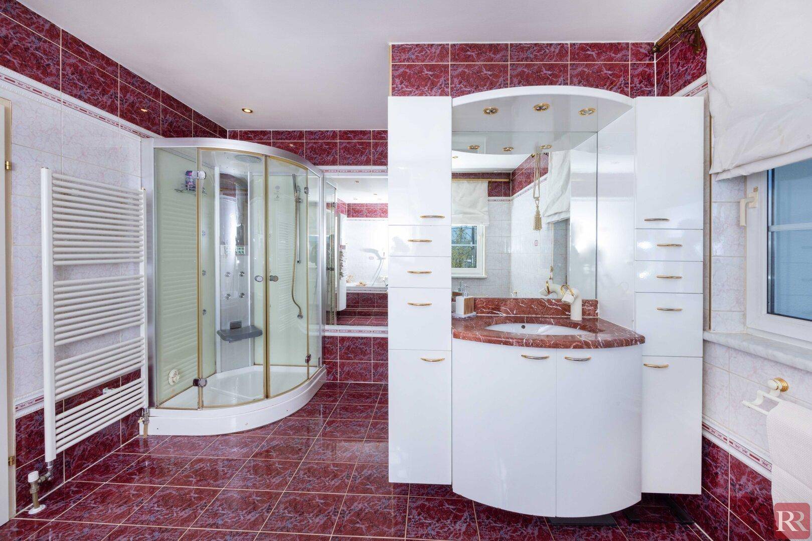 Modernes Badezimmer mit Duschkabine, Einzelwaschbecken und roten Fliesen, hell und funktional.