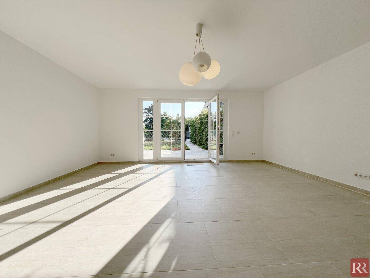 Helles Wohnzimmer mit großen Glastüren, die direkten Zugang zum Garten bieten.