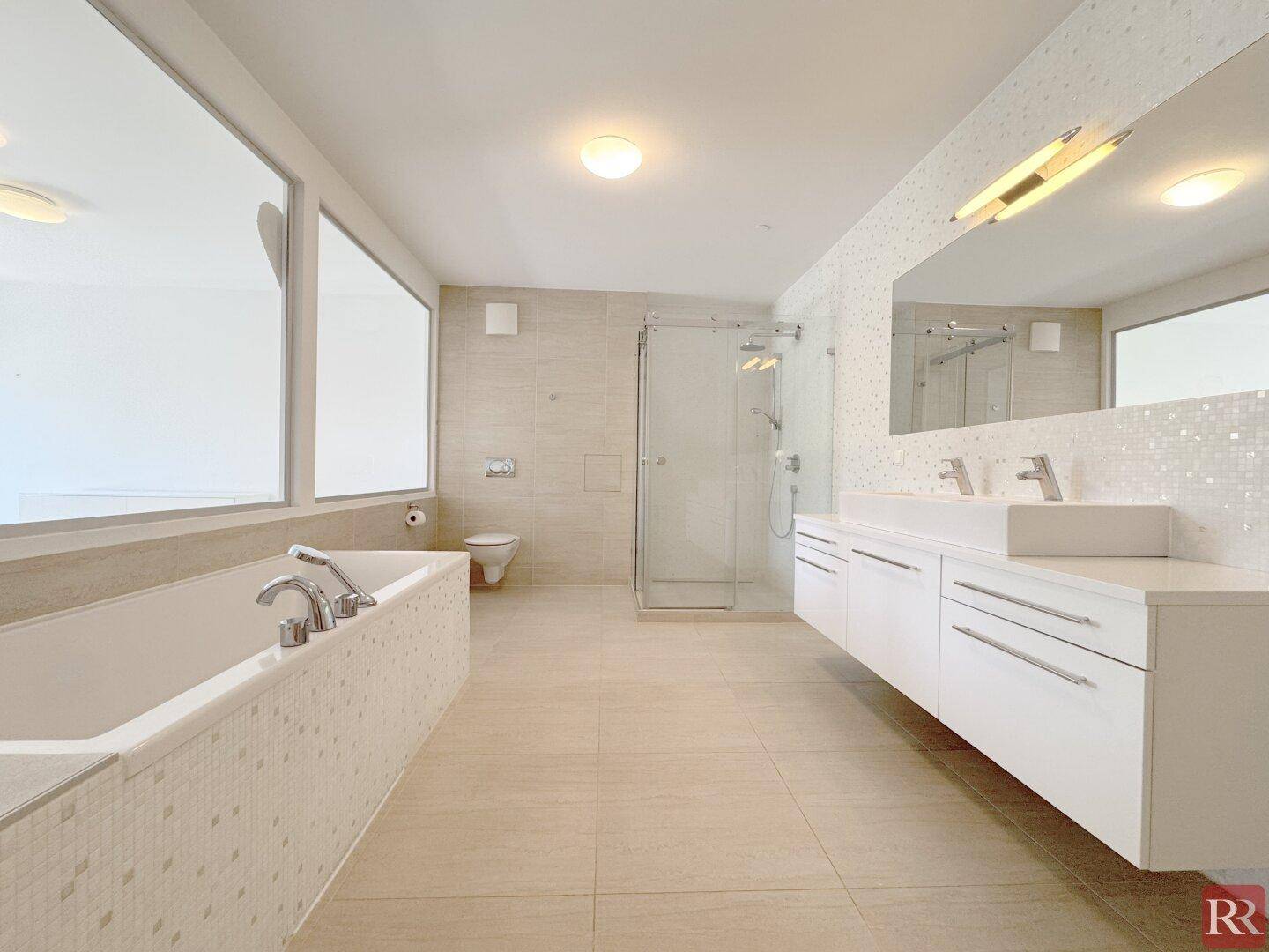 Modernes Badezimmer mit Badewanne, begehbarer Dusche und Doppelwaschbecken.