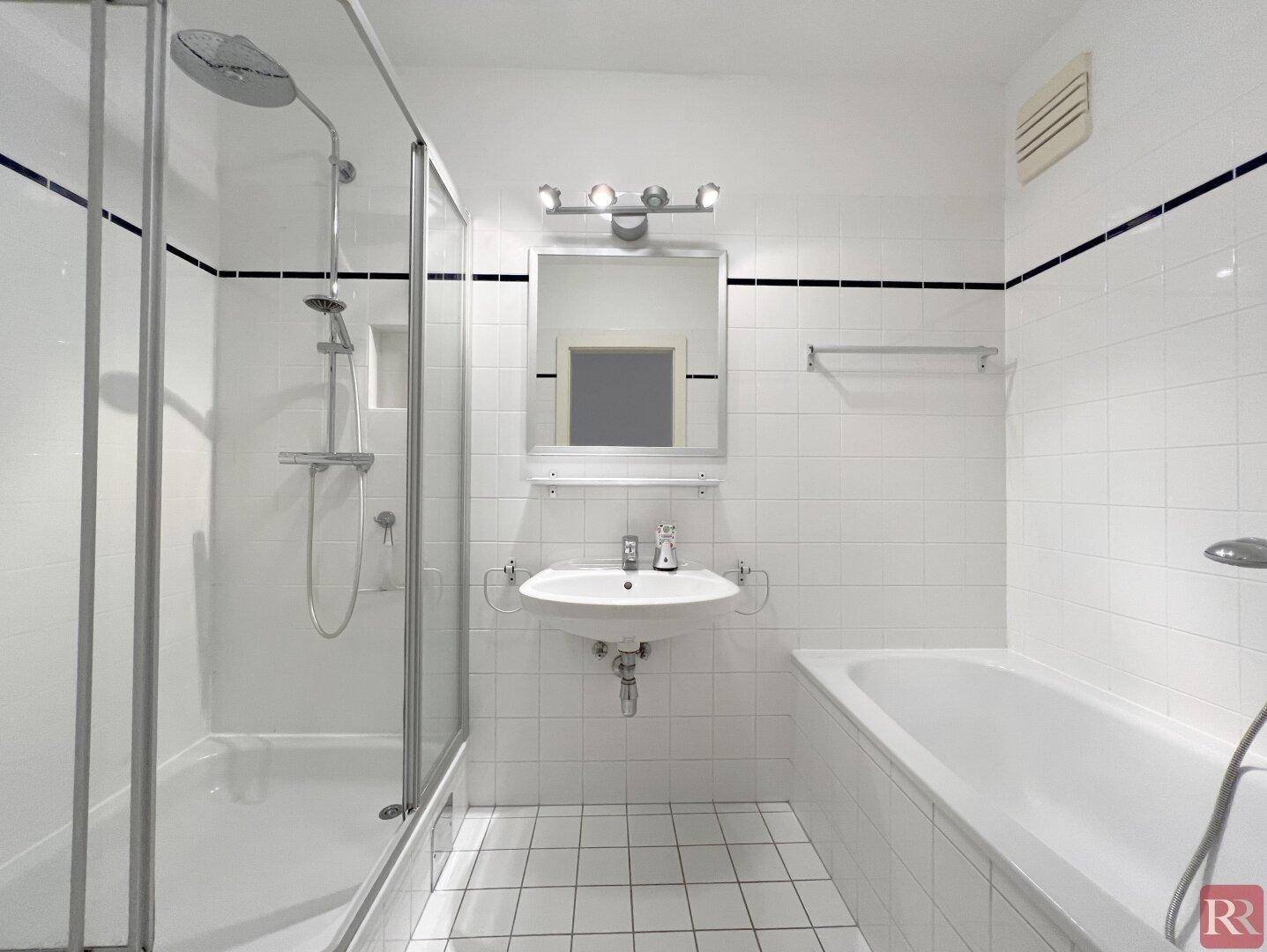 Modernes Badezimmer mit weißen Fliesen, Duschkabine, Badewanne und Einzelwaschbecken.