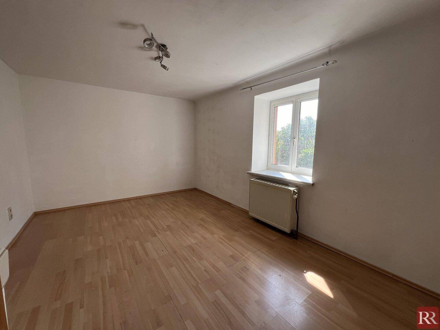 Heller, leerer Raum mit Laminatboden und weiß gestrichenen Wänden, bereit zur Gestaltung.